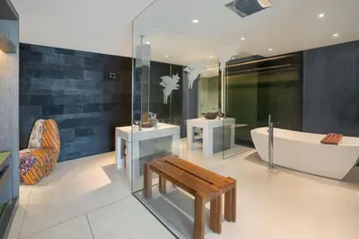 a bathroom with two sinks and a tub and a bench at W Bali - Seminyak in Seminyak