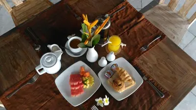 a wooden table with two plates of food on it at Nipuri Resort and Villas Seminyak by Kamara in Seminyak