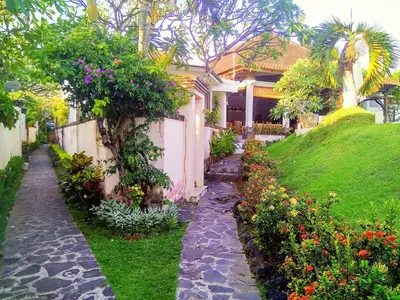 a house with a garden with flowers in front of it at Nipuri Resort and Villas Seminyak by Kamara in Seminyak