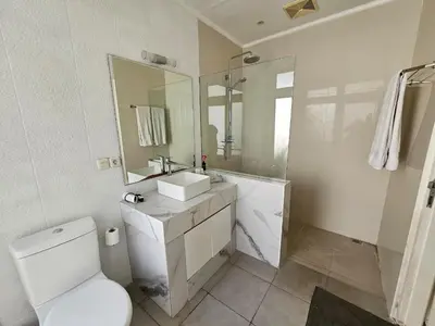 a bathroom with a toilet and a sink and a mirror at Nipuri Resort and Villas Seminyak by Kamara in Seminyak