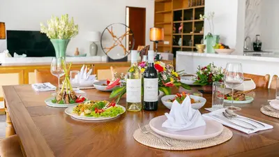 a wooden table with plates of food and wine bottles at Villa Indrani in Canggu
