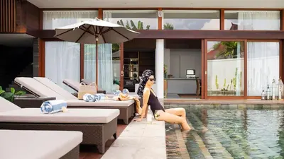 a woman sitting next to a swimming pool at Villa Indrani in Canggu