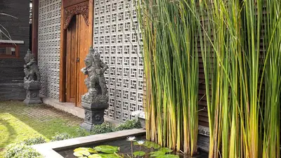 a garden with tall green plants next to a building at Villa Indrani in Canggu