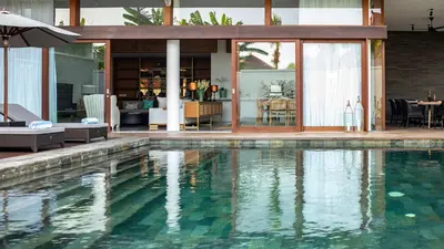 a swimming pool in front of a house at Villa Indrani in Canggu