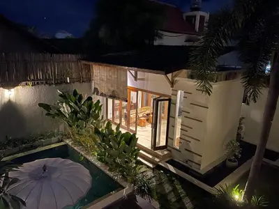 an umbrella in front of a house at night at Balcony Living Apartment in Seminyak