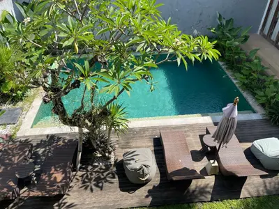 a swimming pool with two chairs and a bird sitting on it at Balcony Living Apartment in Seminyak