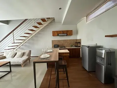 a kitchen and living room with a table and a staircase at Balcony Living Apartment in Seminyak