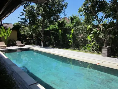 a swimming pool in a yard with trees at Sasa Bali Villas in Seminyak