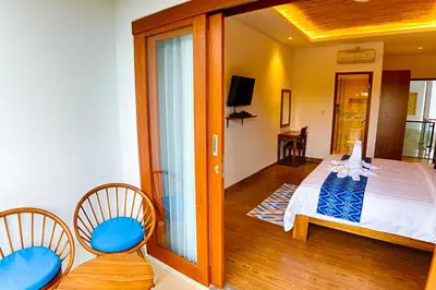 a bedroom with a bed and two chairs and a balcony at Villa Caitlyn, Seminyak - Modern 3 Bedroom Villa with Private Pool! in Seminyak
