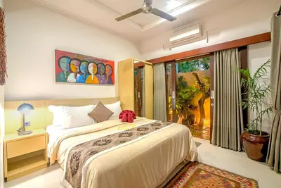 a bedroom with a bed and a painting on the wall at Villa Ellen in Seminyak