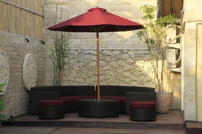 a red umbrella sitting next to a couch and stool at Villa Margaux in Seminyak