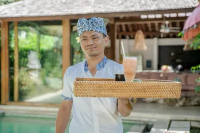 a man holding a tray with a drink on it at Villa Saffira, Seminyak - Pool, Garden, Rooftop - Walk to Beach and Cafes! in Seminyak
