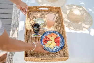 a person holding a plate of fruit on a table at Villa Saffira, Seminyak - Pool, Garden, Rooftop - Walk to Beach and Cafes! in Seminyak