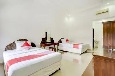 a hotel room with two beds and a desk at Hotel O Ratu in Denpasar