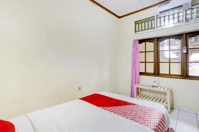 a bedroom with a bed and a window at Hotel O Ratu in Denpasar