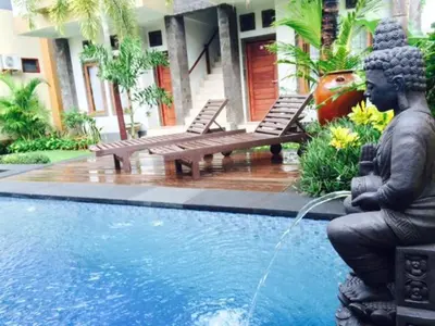 a statue sitting next to a pool with a fountain at Tanjung Sari Inn in Nusa Dua