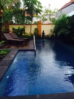 a large blue swimming pool in a yard at Tanjung Sari Inn in Nusa Dua