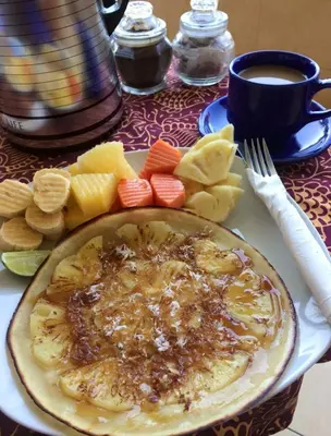 a table with a plate of food and a cup of coffee at Tanjung Sari Inn in Nusa Dua