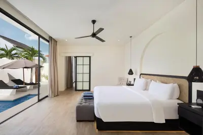 a bedroom with a large white bed and a balcony at The Grand Daha Luxury Villas in Seminyak