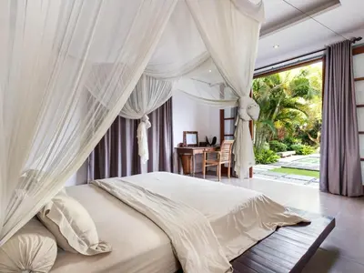 a bedroom with a white canopy bed with a desk at Villa Arte by Villa Finder in Seminyak