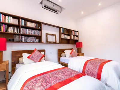 two beds in a room with book shelves at Villa Arte by Villa Finder in Seminyak
