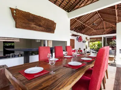 a dining room with a wooden table and red chairs at Villa Arte by Villa Finder in Seminyak