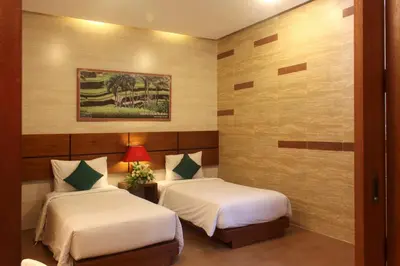 a hotel room with two beds and a painting on the wall at The Green Zhurga Suite Seminyak in Kerobokan