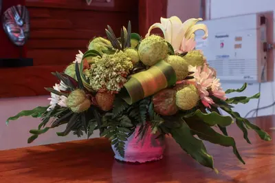 a vase filled with flowers and fruit on a table at The Green Zhurga Suite Seminyak in Kerobokan