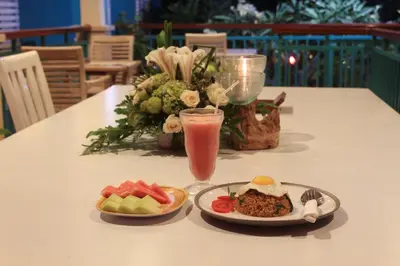a table with a plate of food and a drink at The Green Zhurga Suite Seminyak in Kerobokan
