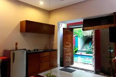 a kitchen with a refrigerator and a door to a yard at The Green Zhurga Suite Seminyak in Kerobokan