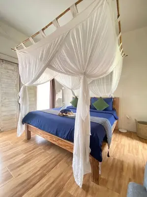 a bedroom with a canopy bed with blue sheets at Kubu Guest House in Seminyak
