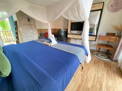 a bedroom with a blue bed with a canopy at Kubu Guest House in Seminyak