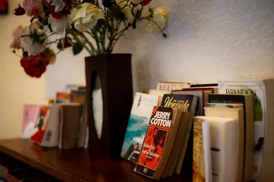 a table with a vase of flowers and books at Fourteen Roses Beach Hotel in Legian