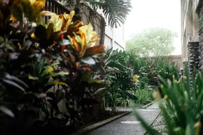 a garden with yellow and orange flowers and plants at Fourteen Roses Beach Hotel in Legian