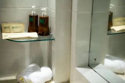 a bathroom with two bottles of soap and towels at Fourteen Roses Beach Hotel in Legian