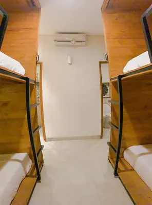 a room with three bunk beds and a white wall at DBeds Kuta Beach in Kuta