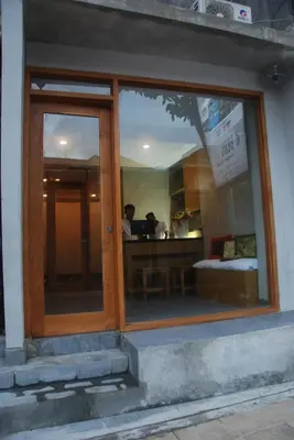a store window with a reflection of a man sitting at a table at DBeds Kuta Beach in Kuta