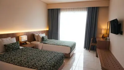 a hotel room with two beds and a window at Tusita Boutique Hotel in Kuta