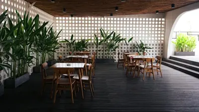 a restaurant with wooden tables and chairs and plants at Tusita Boutique Hotel in Kuta