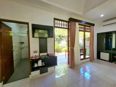 a large bathroom with a shower and a glass door at Satriya Cottages in Kuta