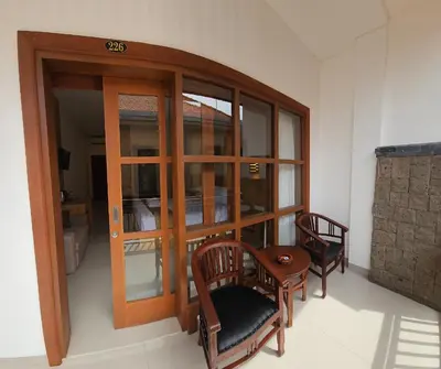 a room with two chairs and a glass door at Satriya Cottages in Kuta