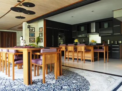 a kitchen with black cabinets and a wooden table and chairs at Pronoia Beach Resort in Jimbaran