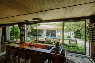 a dining room with a table and a view of a pool at Pronoia Beach Resort in Jimbaran