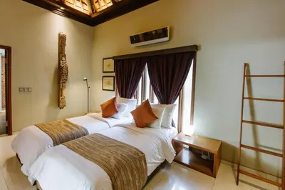 two beds in a hotel room with a window at Pronoia Beach Resort in Jimbaran