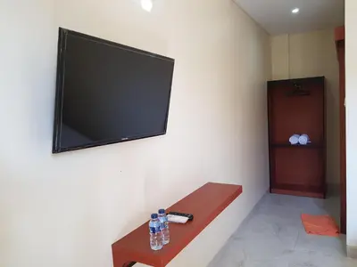 a flat screen tv hanging on a wall at Praba Guesthouse in Kuta