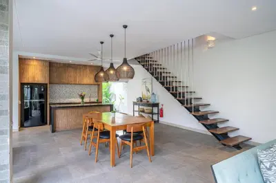 a kitchen and dining room with a wooden table and a staircase at Villa Jekumah 3 in Seminyak
