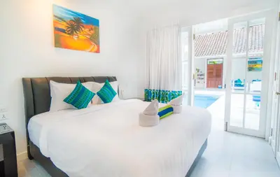 a bedroom with a large white bed and a pool at Villa Ley Double Six by Best Deals Asia Hospitality in Seminyak