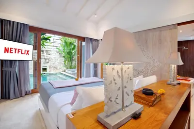 a bedroom with a bed and a table with a lamp at The Jimbaran Villa by Ini Vie Hospitality in Jimbaran