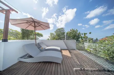 a hammock with an umbrella on a deck at The Jimbaran Villa by Ini Vie Hospitality in Jimbaran