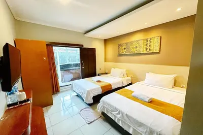 a hotel room with two beds and a television at Lembayung Sari Homestay in Denpasar